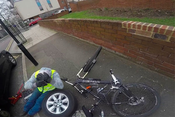 Un ciclista torpe por la acera y un conductor reparando el coche en plena calle: una mala (aunque divertida) combinación